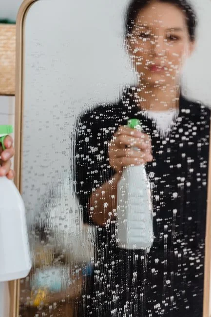 who-we-are A person in protective gear disinfecting a carpet with a fumigation device indoors.
